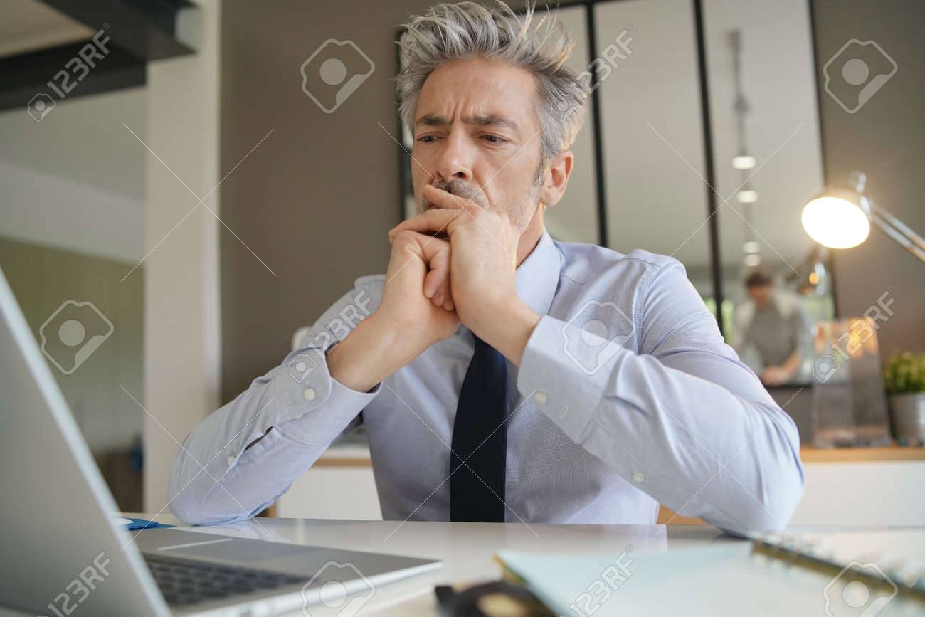 Handsome businessman in office contemplating - 120544552 Handsome businessman in office contemplating - 120544552