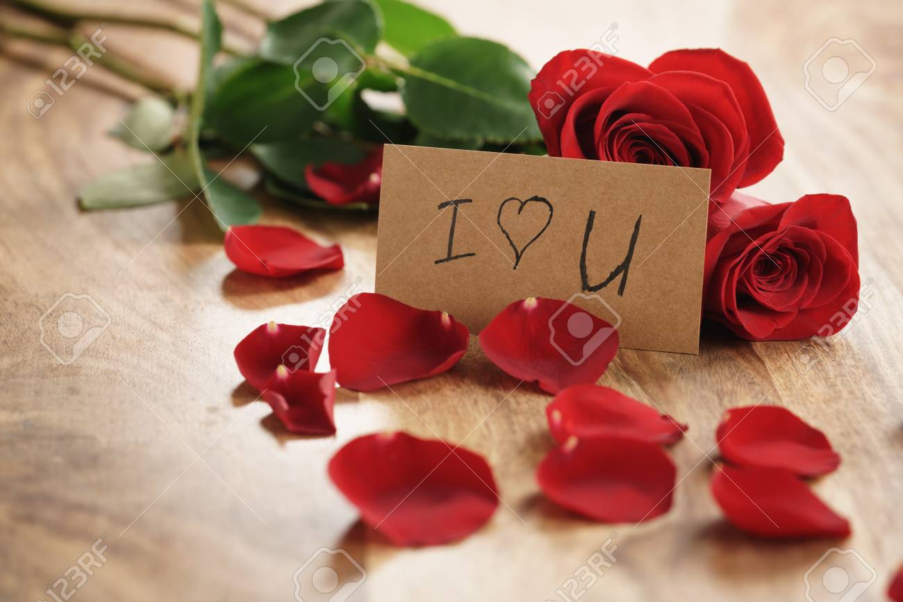 Three Red Roses And Petals On Old Wood Table With I Love You Paper ...