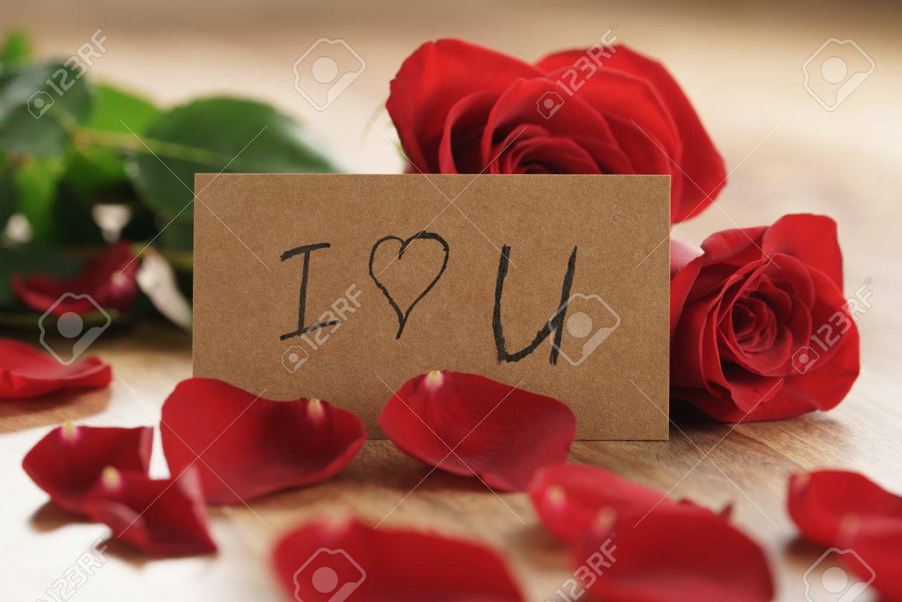 Three Red Roses And Petals On Old Wood Table With I Love You Paper ...