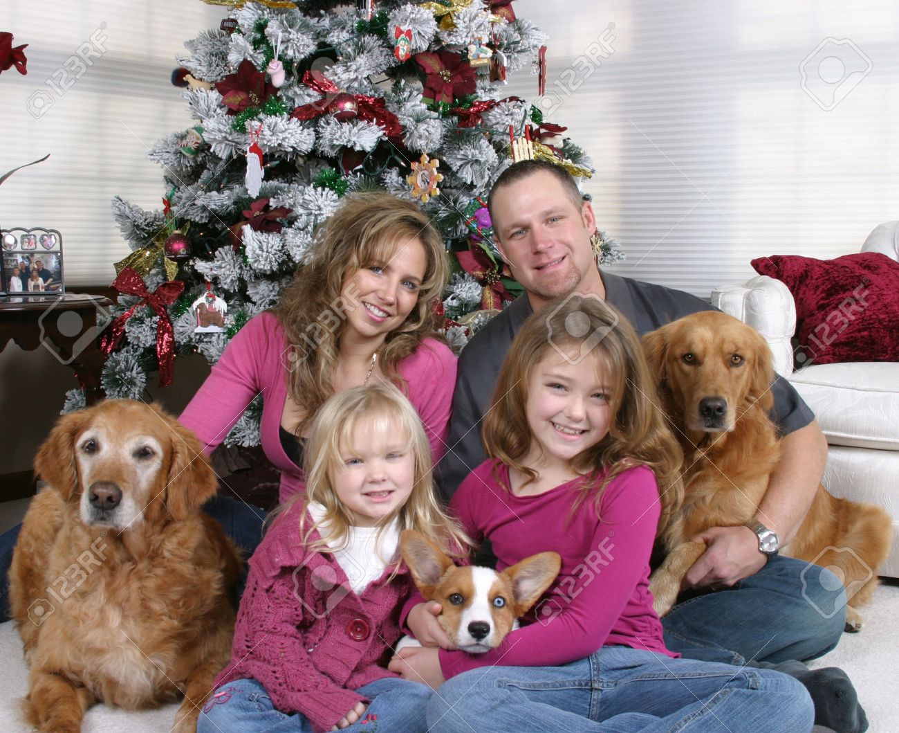 smiling family and dogs sitting by Christmas tree