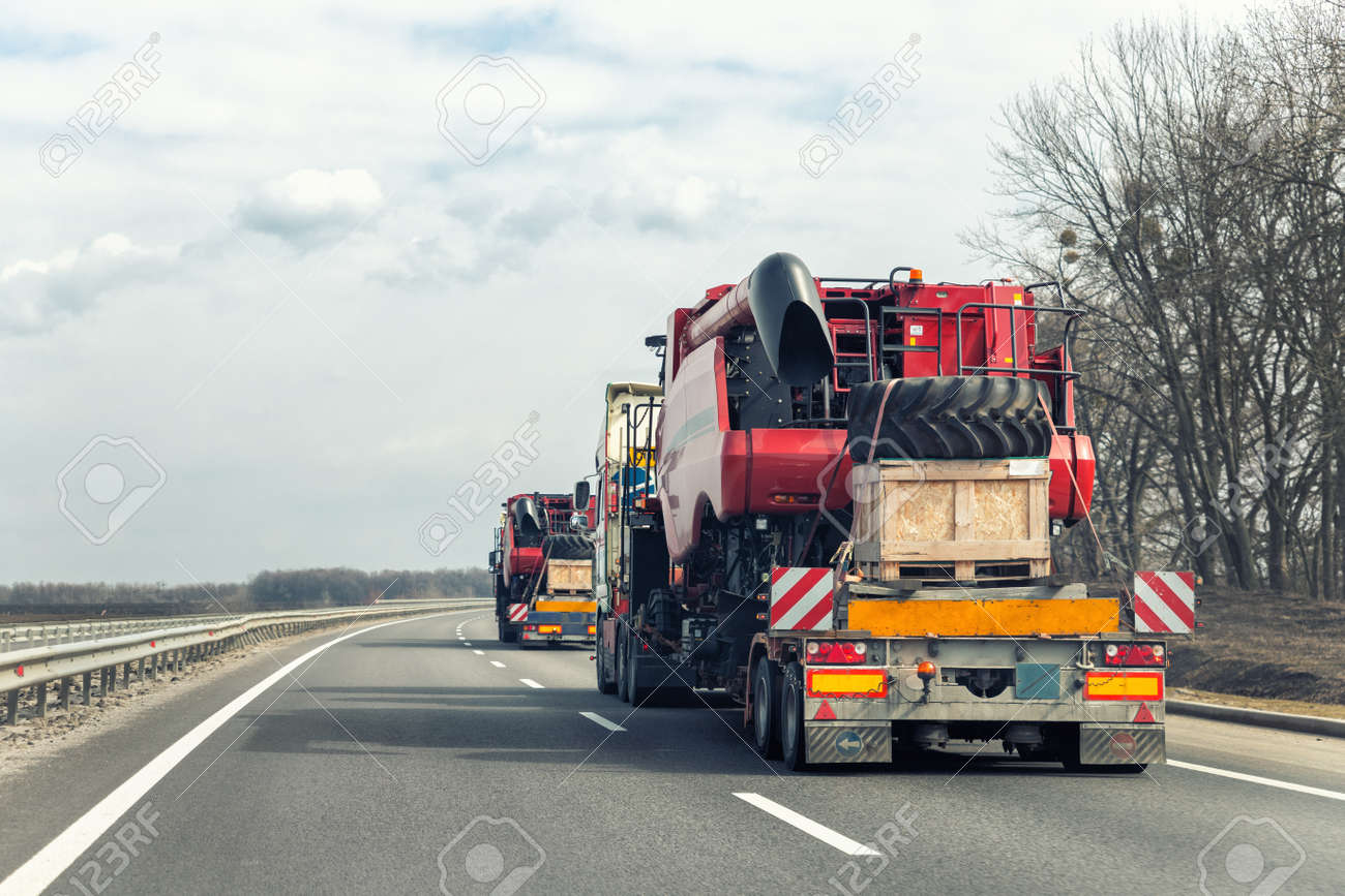 Many heavy industrial truck with semi trailer platform transport disassembled combine harvester machine on common highway road on sunset or sunrise day. Agricultural equipment transportation service - 166673822 Many heavy industrial truck with semi trailer platform transport disassembled combine harvester machine on common highway road on sunset or sunrise day. Agricultural equipment transportation service - 166673822