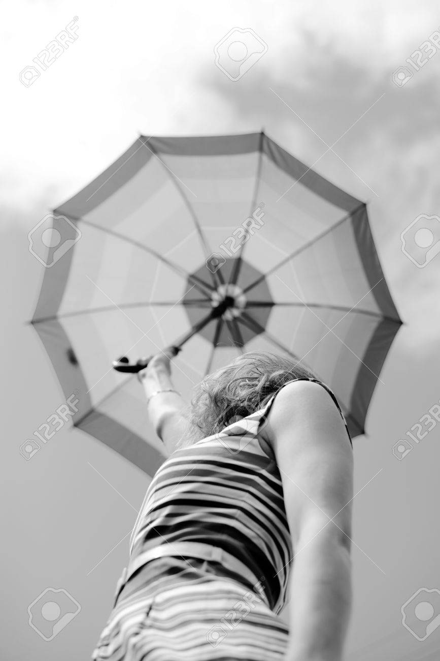 Fotografía En Blanco Y Negro La Hembra Elegante Bajo El Paraguas Mirando Hacia Arriba En El Cielo De La Nube. Mujer En Traje De Rayas Aumento Sombrilla. Fotos, Retratos, Imágenes Y