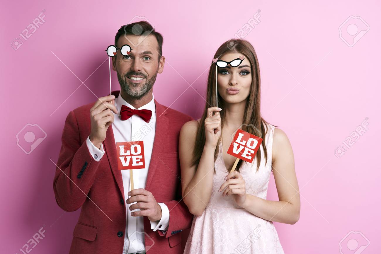 Portrait of couple with photo booth partying - 89280185 Portrait of couple with photo booth partying - 89280185