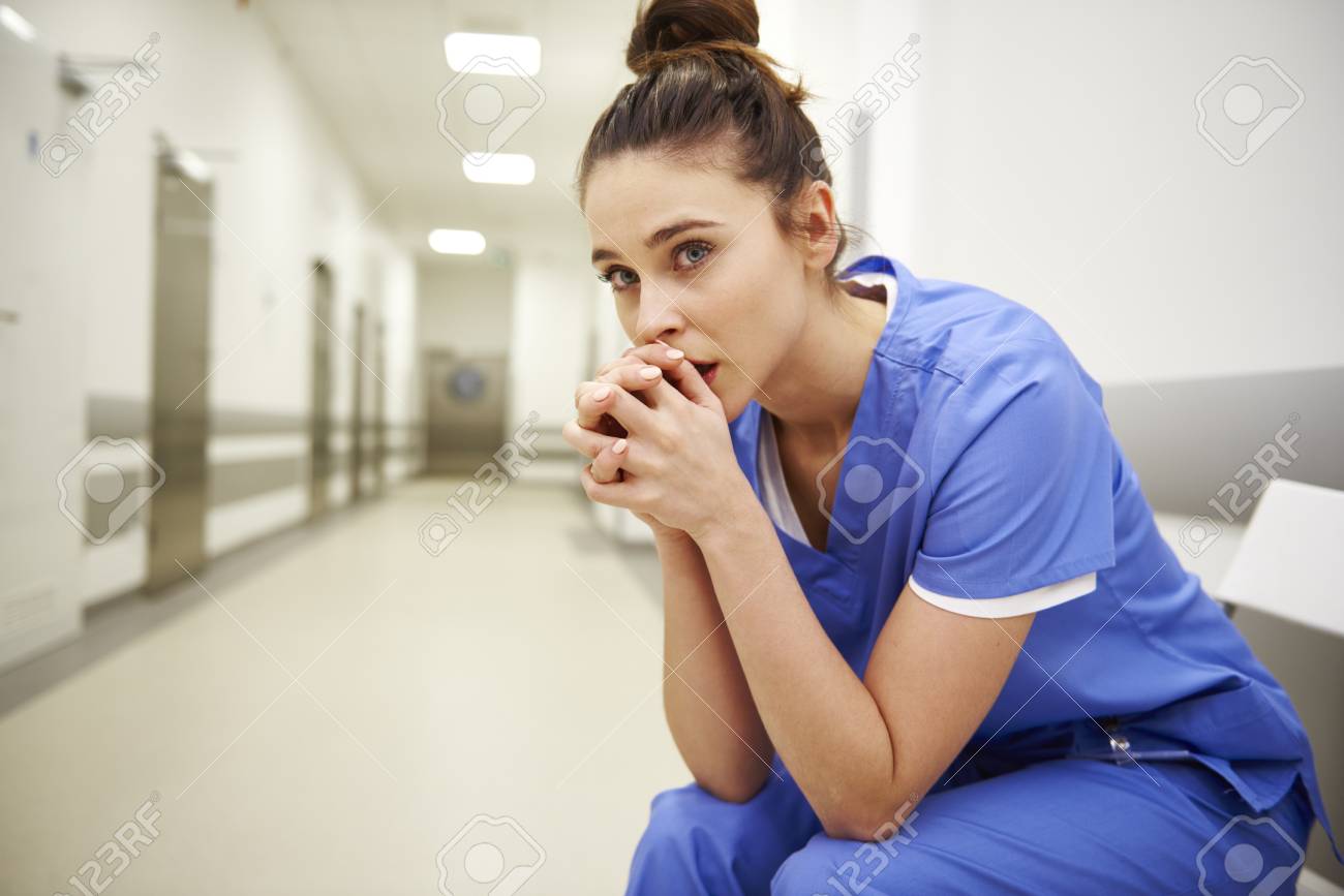 Close up of upset female nurse in the corridor - 119524410 Close up of upset female nurse in the corridor - 119524410
