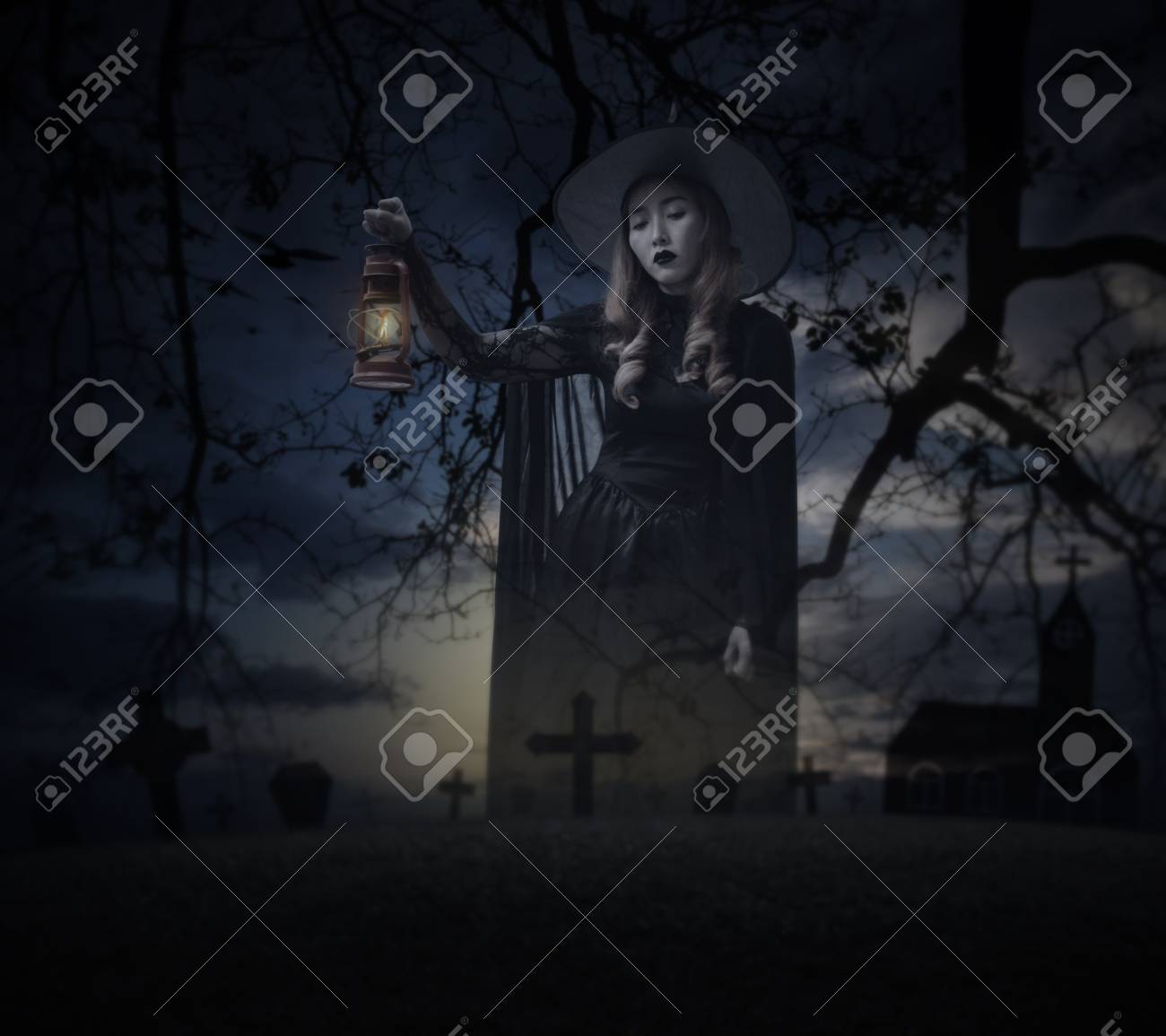 Bruxa Do Dia Das Bruxas Que Guarda A Lâmpada Antiga Que Está Sobre A Grama, Árvore Morta, Cruz, Pássaros Com A Igreja Sobre O Céu Nublado Assustador, Conceito Do Mistério Do Dia
