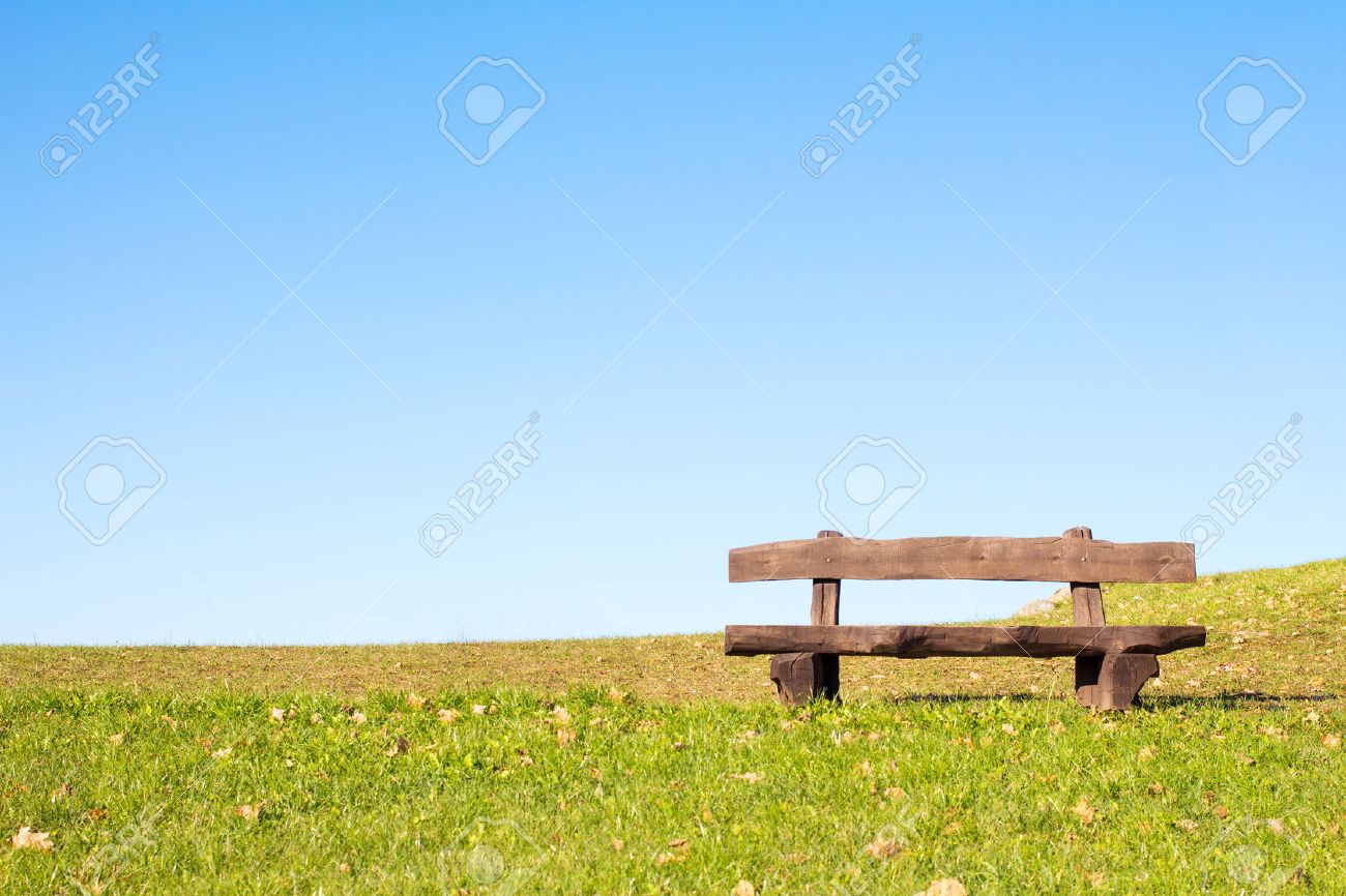 A calm place to rest and relax. An empty wooden bench over a serene blue sky waiting for a hiker or casual walker to sit and rest. - 47210341 A calm place to rest and relax. An empty wooden bench over a serene blue sky waiting for a hiker or casual walker to sit and rest. - 47210341