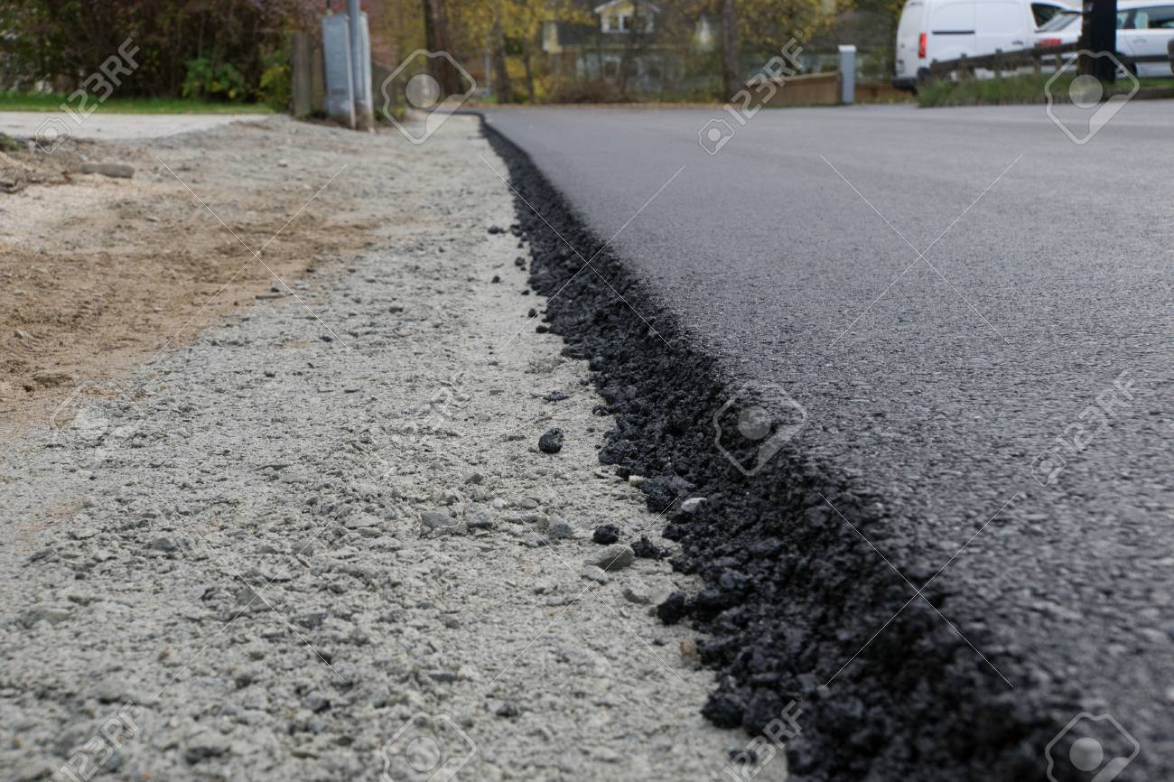 freshly laid black bitumen asphalt with a high edge to the gravel laid asphalt