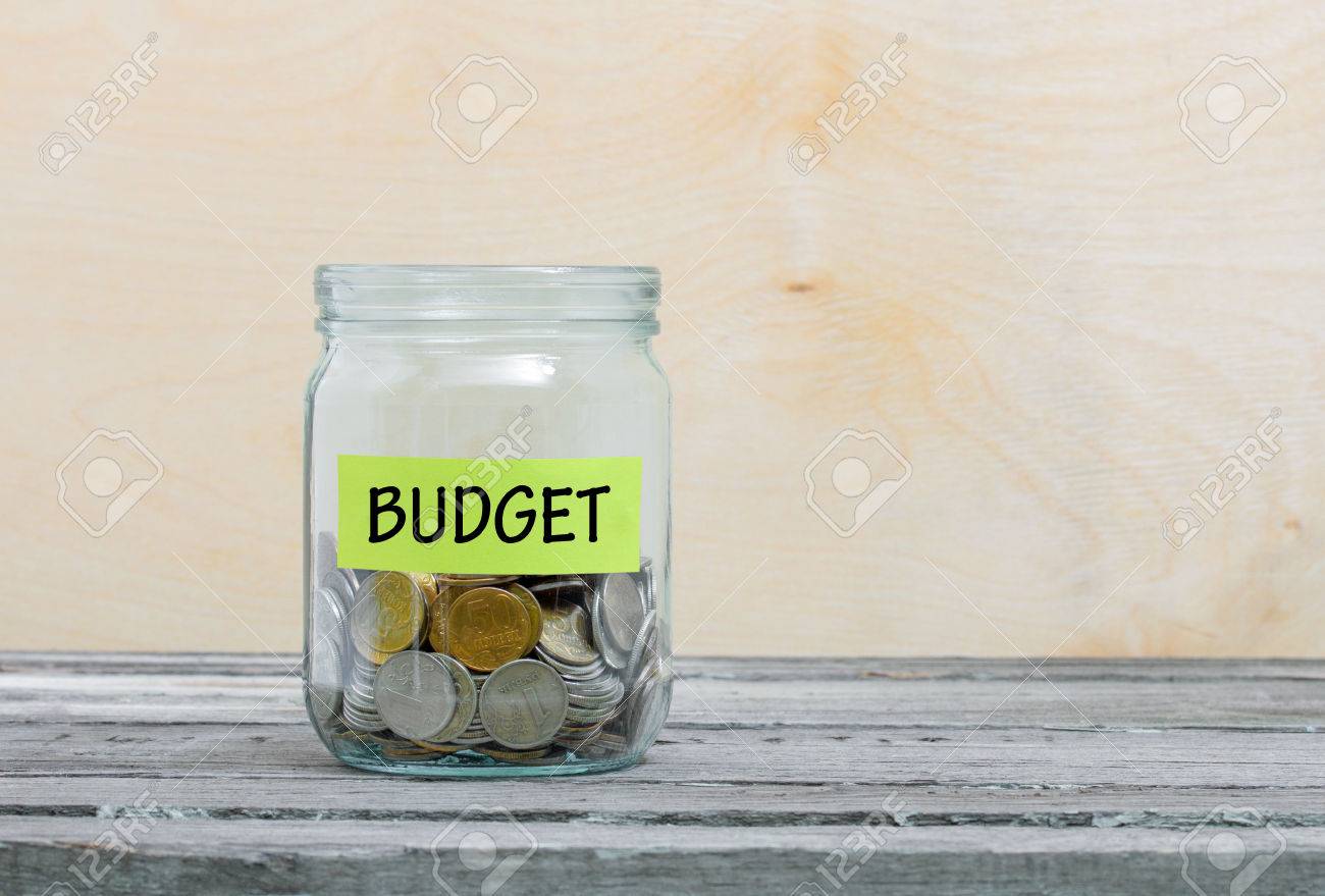 Label on a glass jar with the inscription - budget. Glass jar with coins. Financial concept on wooden background - 55369542 Label on a glass jar with the inscription - budget. Glass jar with coins. Financial concept on wooden background - 55369542