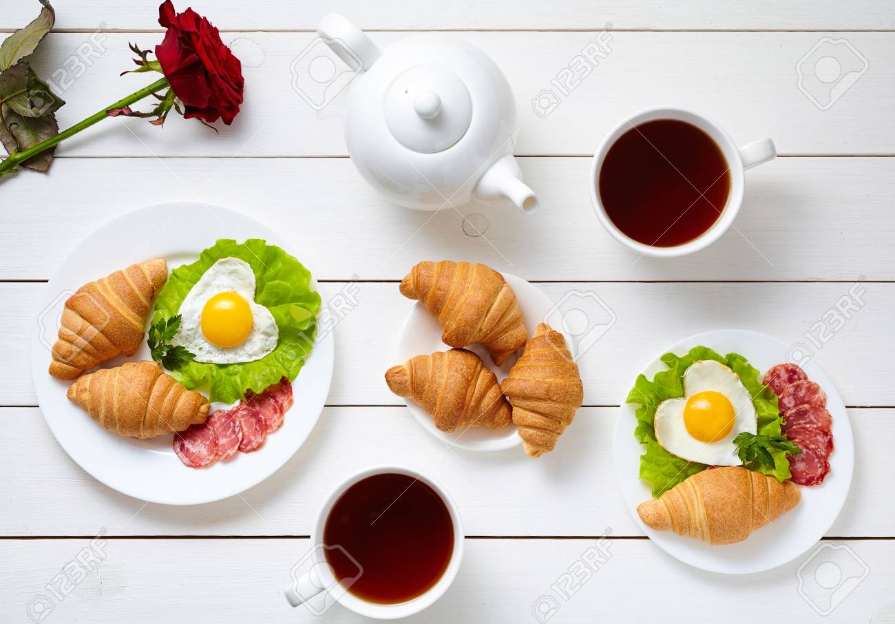 Petit Dejeuner Romantique Pour La Saint Valentin Avec Des Oeufs En Forme De Coeur Salade Croissants Fleur Rose Et The Sur Fond De Table En Bois Blanc Concept Alimentaire De L Amour Vue De Dessus