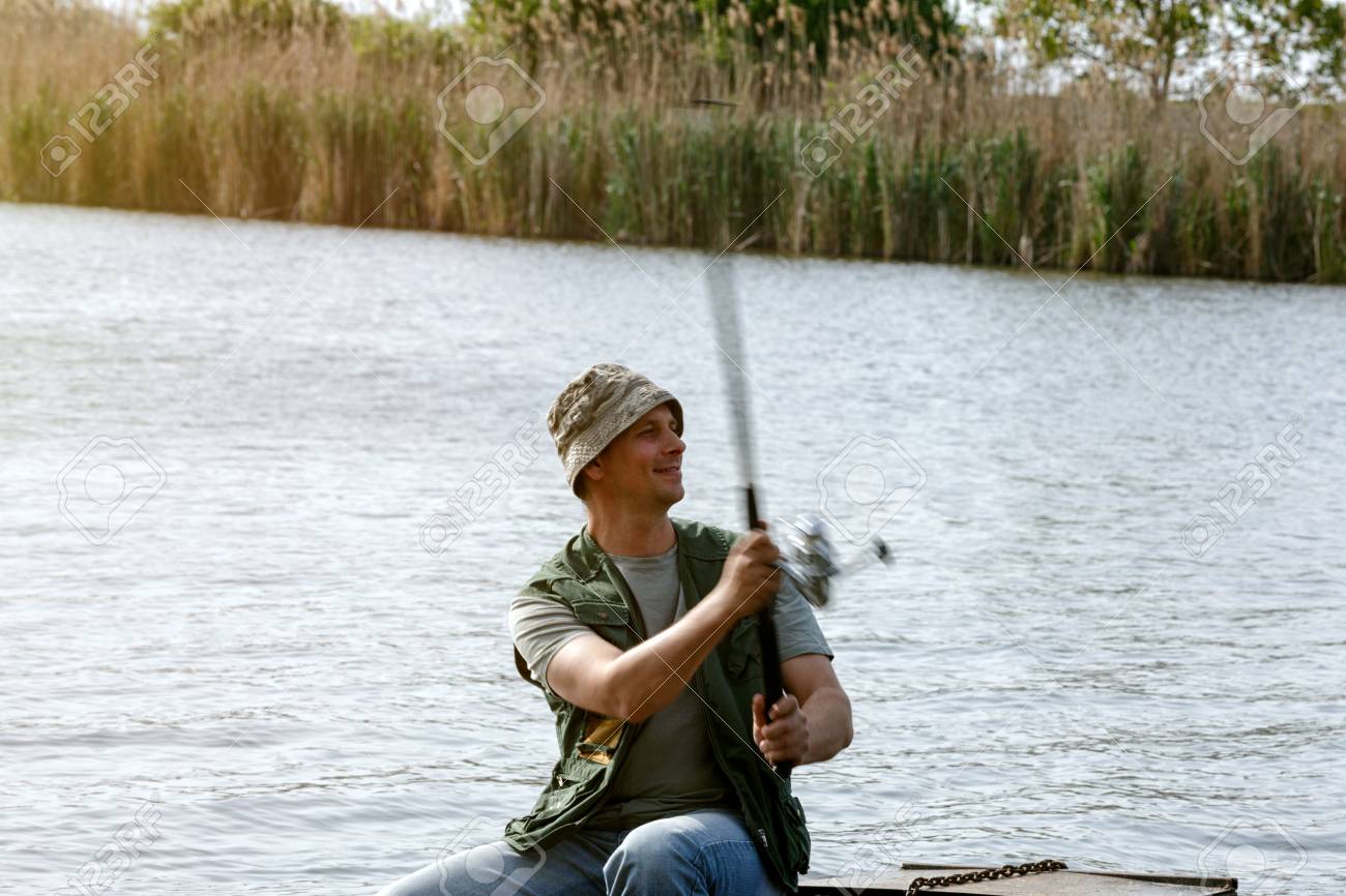 River Fishing Portrait Of Man Catching Fish In Boat Stock Photo