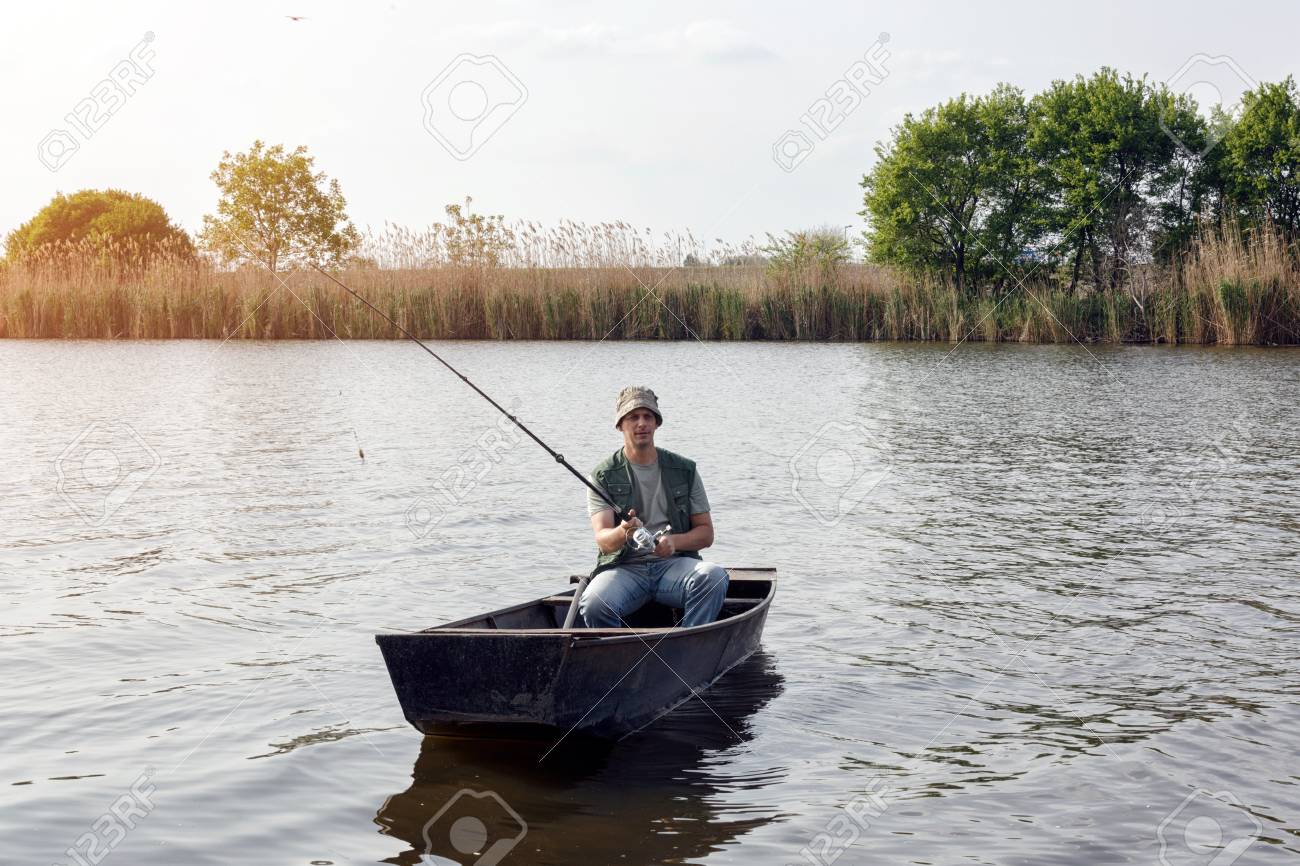 River Fishing Man Catching Fish In Boat Stock Photo Picture And
