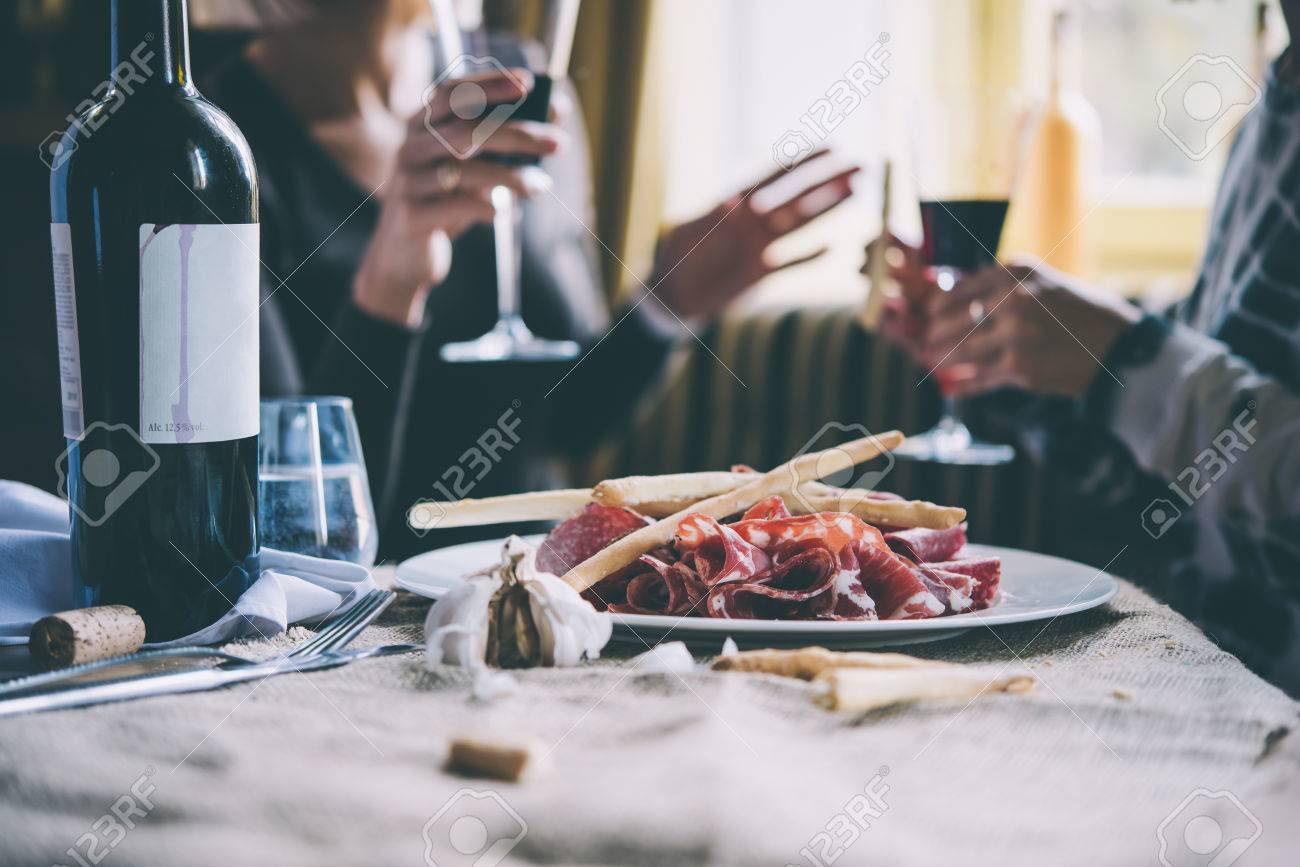 Restaurant or bar table with plate of appetizers and wine. Two people talking on background. Toned picture - 50645753 Restaurant or bar table with plate of appetizers and wine. Two people talking on background. Toned picture - 50645753