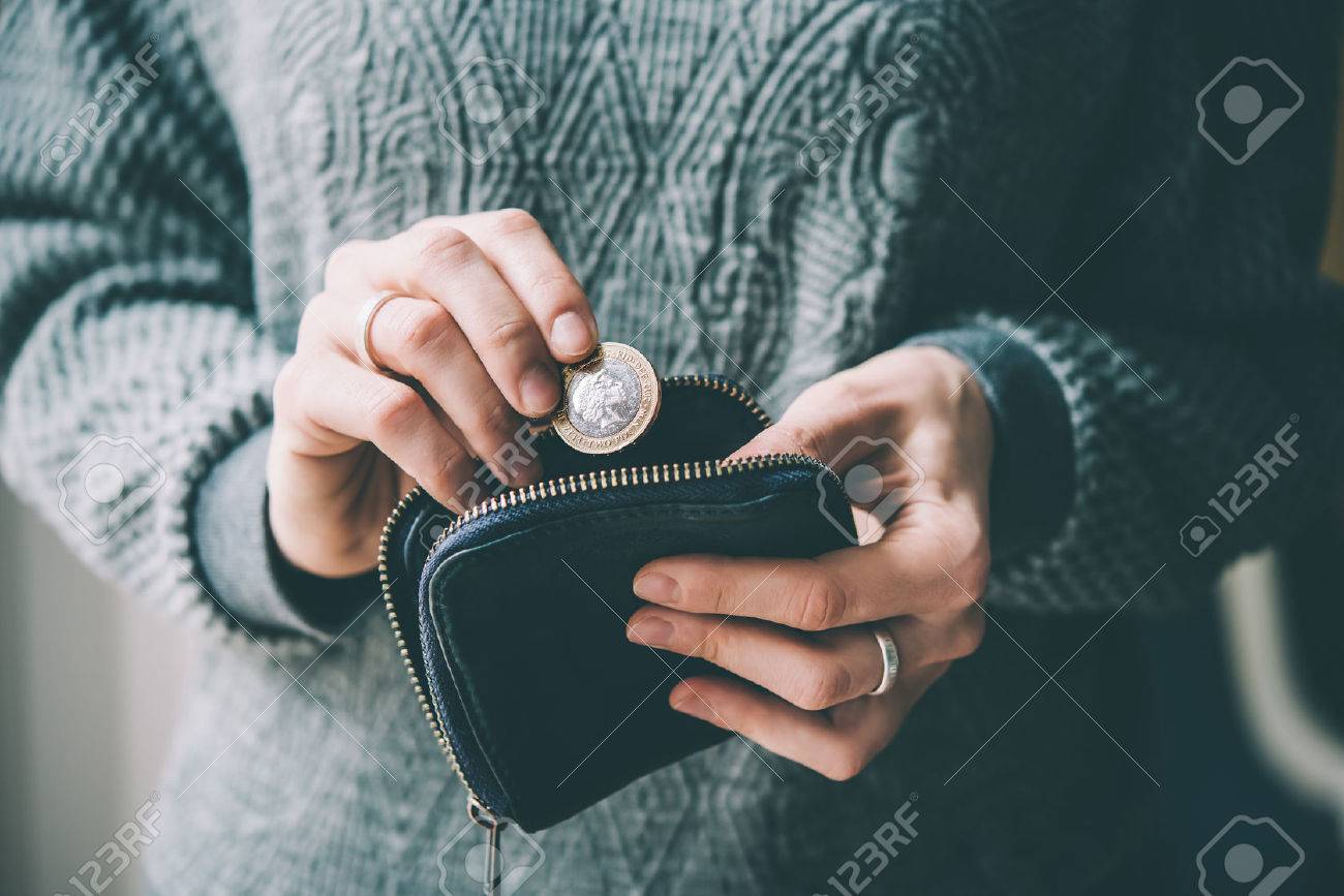 Hands holding british pound coin and small money pouch. Toned picture - 55411679 Hands holding british pound coin and small money pouch. Toned picture - 55411679