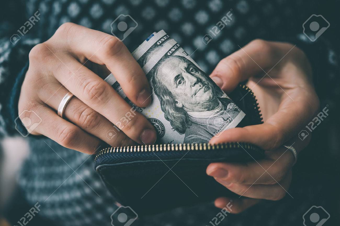 Hands holding us dollar bills and small money pouch. Toned picture - 55416821 Hands holding us dollar bills and small money pouch. Toned picture - 55416821