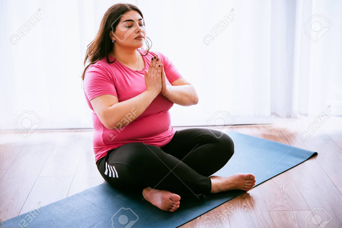 Beautiful plus size girl meditating indoors. Yoga and wellness concept - 74788036 Beautiful plus size girl meditating indoors. Yoga and wellness concept - 74788036