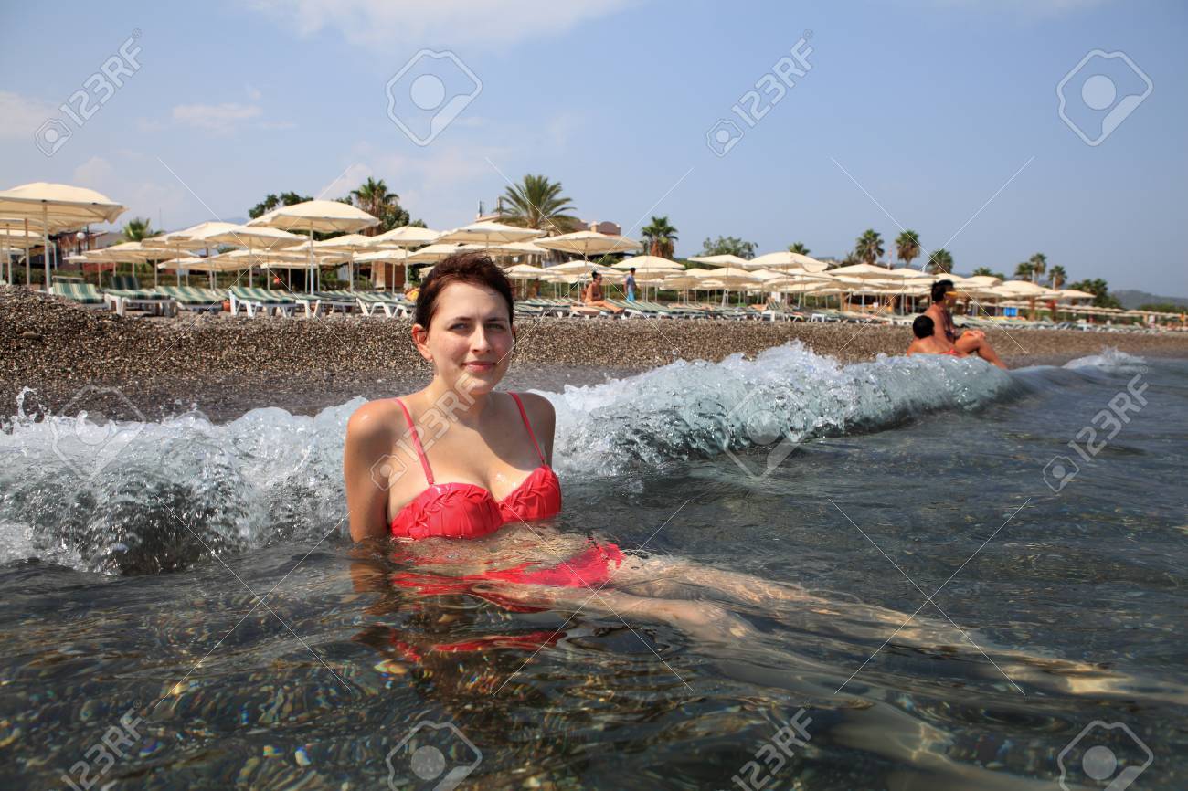 girl sitting at the pebble the beach at the surf line on background