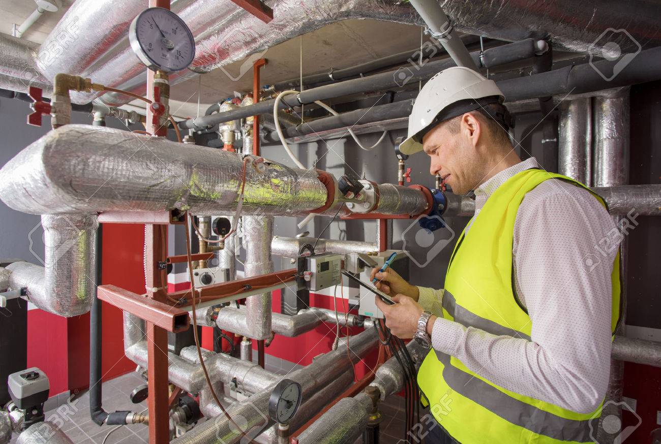 Man in helmet writing down measurements in heat and airconditioning system panel - 75727088 Man in helmet writing down measurements in heat and airconditioning system panel - 75727088
