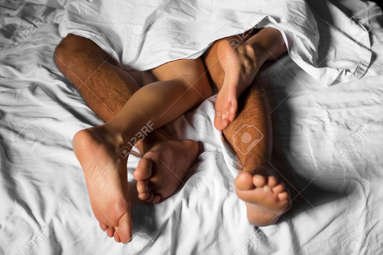 Couple legs entwined under sheets