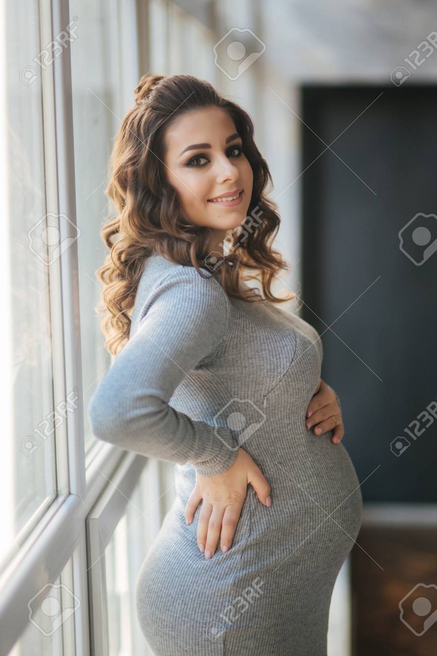 Beautiful Pregnant Woman Walks In The House Near A Large Window