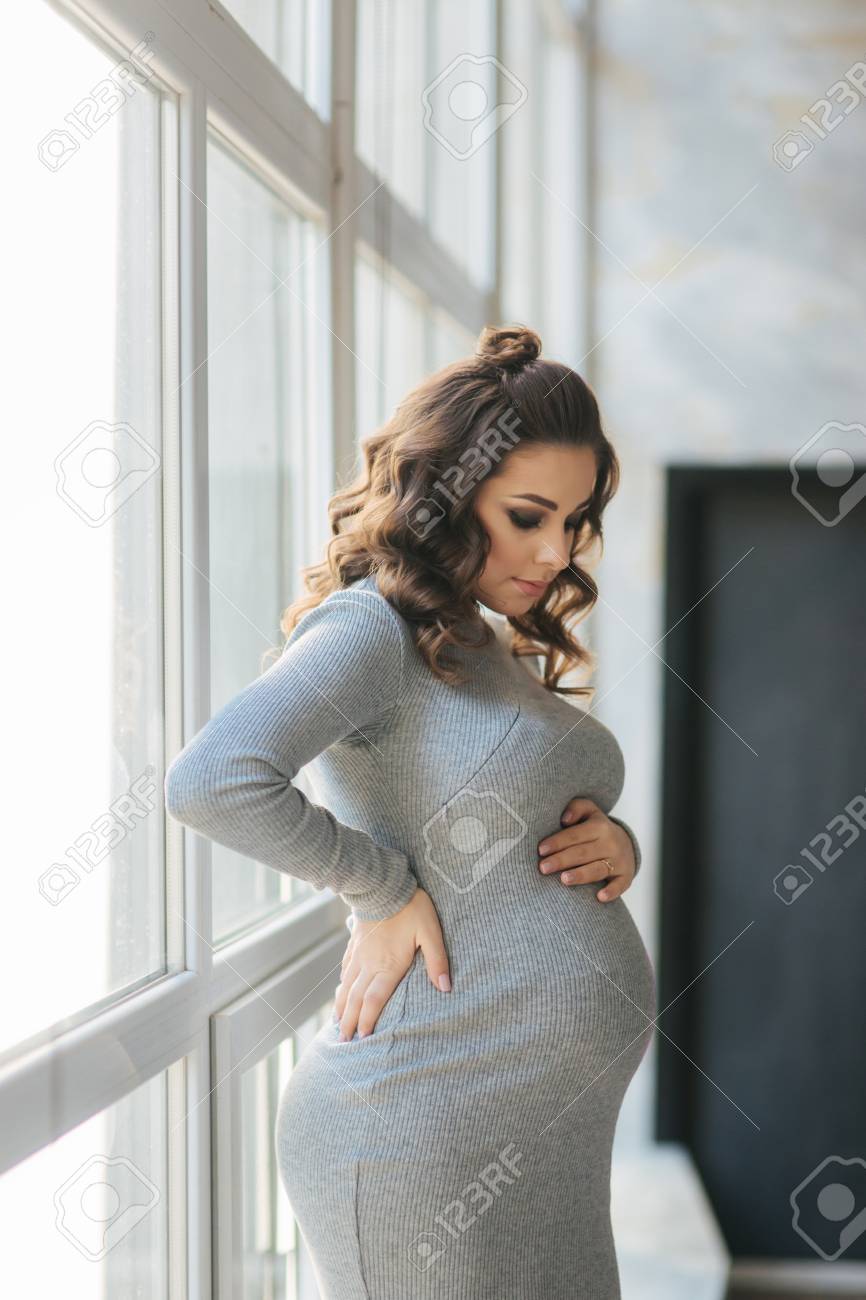 Beautiful Pregnant Woman Walks In The House Near A Large Window