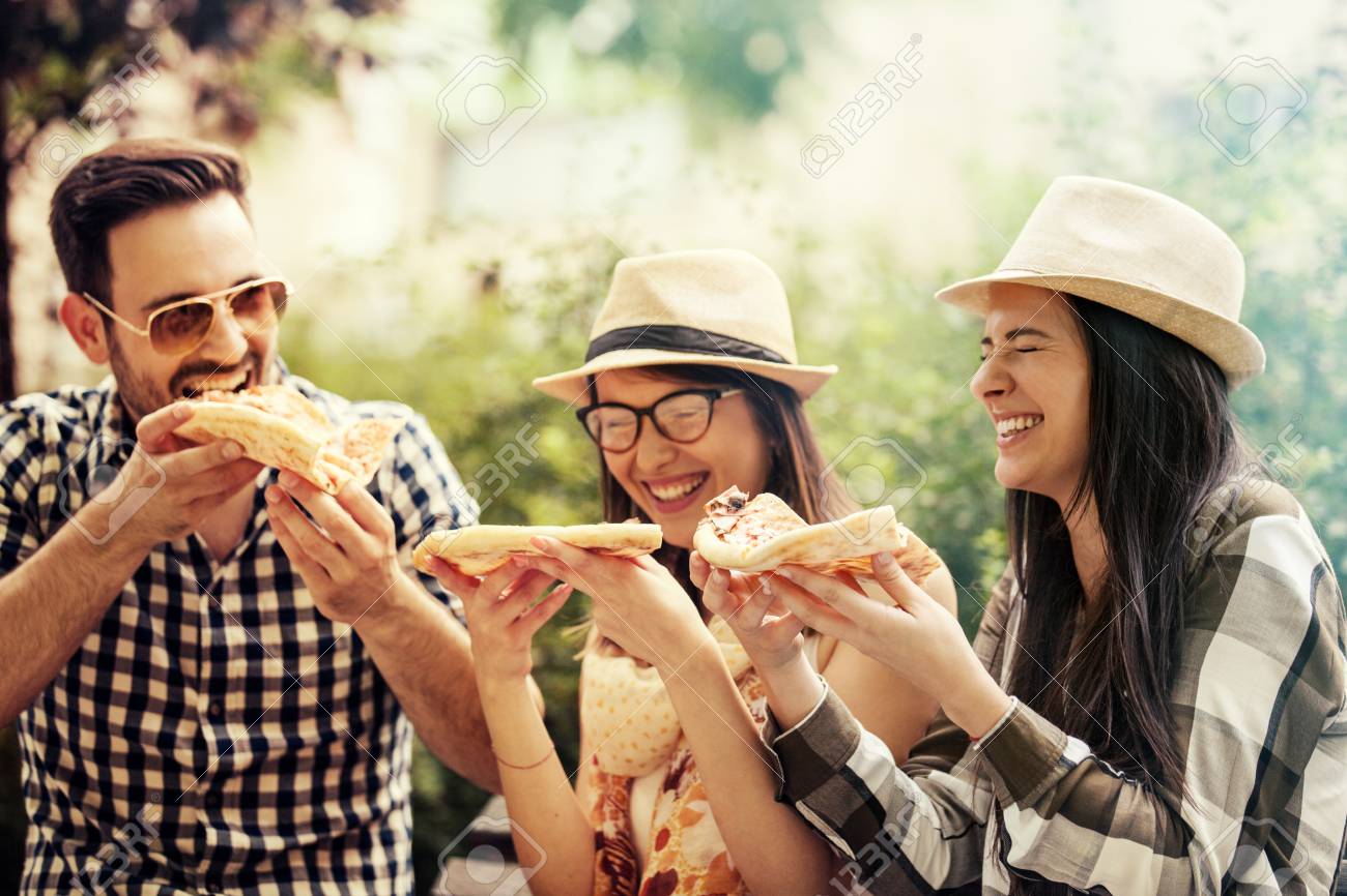 Group of young people having fun in the park and eating pizza. - 65155942 Group of young people having fun in the park and eating pizza. - 65155942