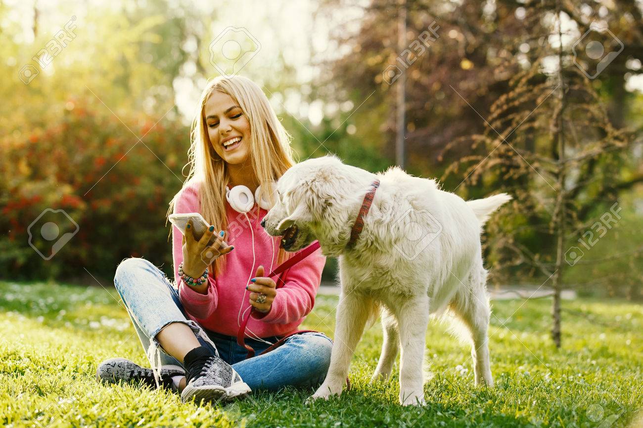 Young blonde woman is relaxing in the park with her retriever. - 84633093 Young blonde woman is relaxing in the park with her retriever. - 84633093