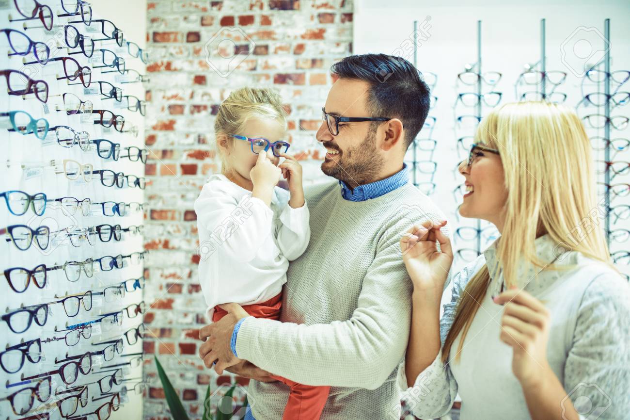 Happy family choosing glasses in optics store. - 87755456 Happy family choosing glasses in optics store. - 87755456