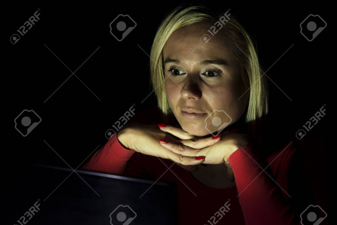 彼女の顔と彼女の手で彼女の頭の上に落ちてコンピューターからのみ光が暗い部屋で夜のコンピューターで働く女性 の写真素材 画像素材 Image