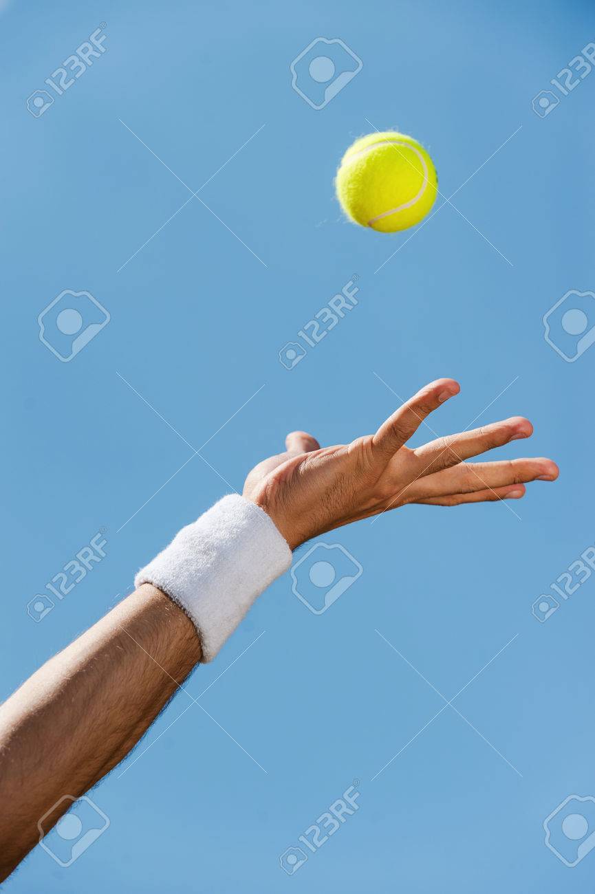 サービング ボール 青い空にテニスボールを投げるリストバンドで男性の手のクローズ アップ の写真素材 画像素材 Image