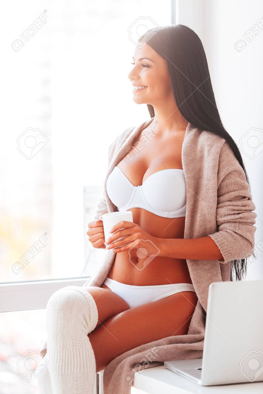 Buenos Días. Hermosa Mujer Joven Ropa Interior Y Beber Café Y Mirando A Través De Una Ventana En Fotos, Retratos, Y Fotografía De Archivo Libres De Derecho. Image