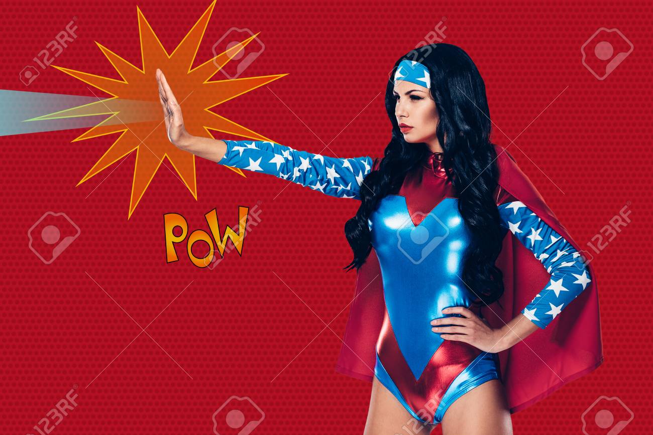 彼女は犯罪を停止することができます スーパー ヒーローの衣装の赤を背景に立っている間彼女の手からビームを撮影の美しい若い女性の側面図 の写真素材 画像素材 Image