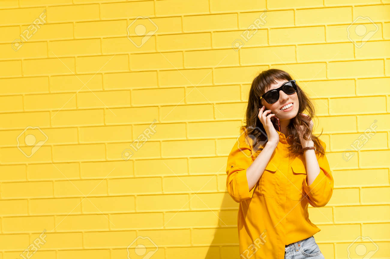 Girl on the phone was told the happy news Girl in yellow shirt against the yellow wall, talking on the phone. Copy space - 152568935 Girl on the phone was told the happy news Girl in yellow shirt against the yellow wall, talking on the phone. Copy space - 152568935