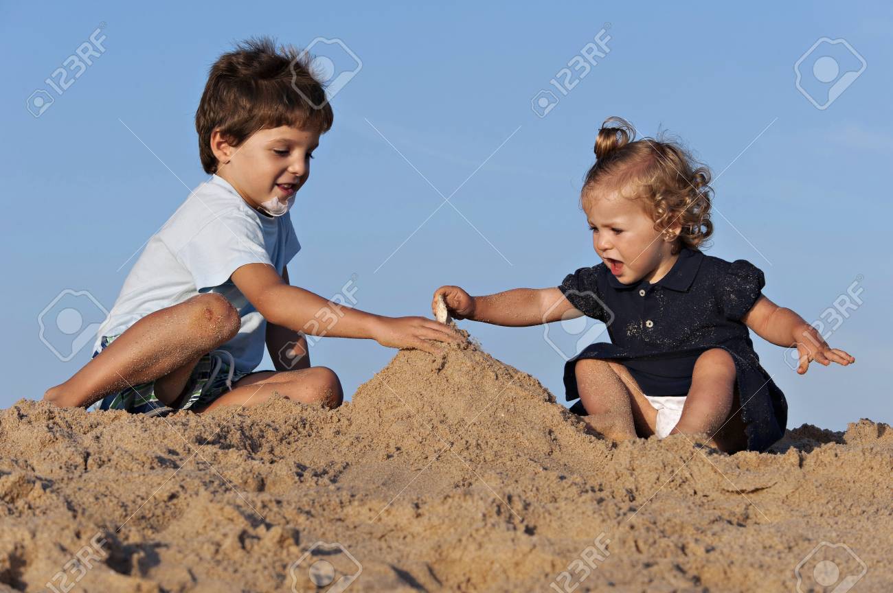 Two children have fun on the beach playing with the sand - 38156582 Two children have fun on the beach playing with the sand - 38156582