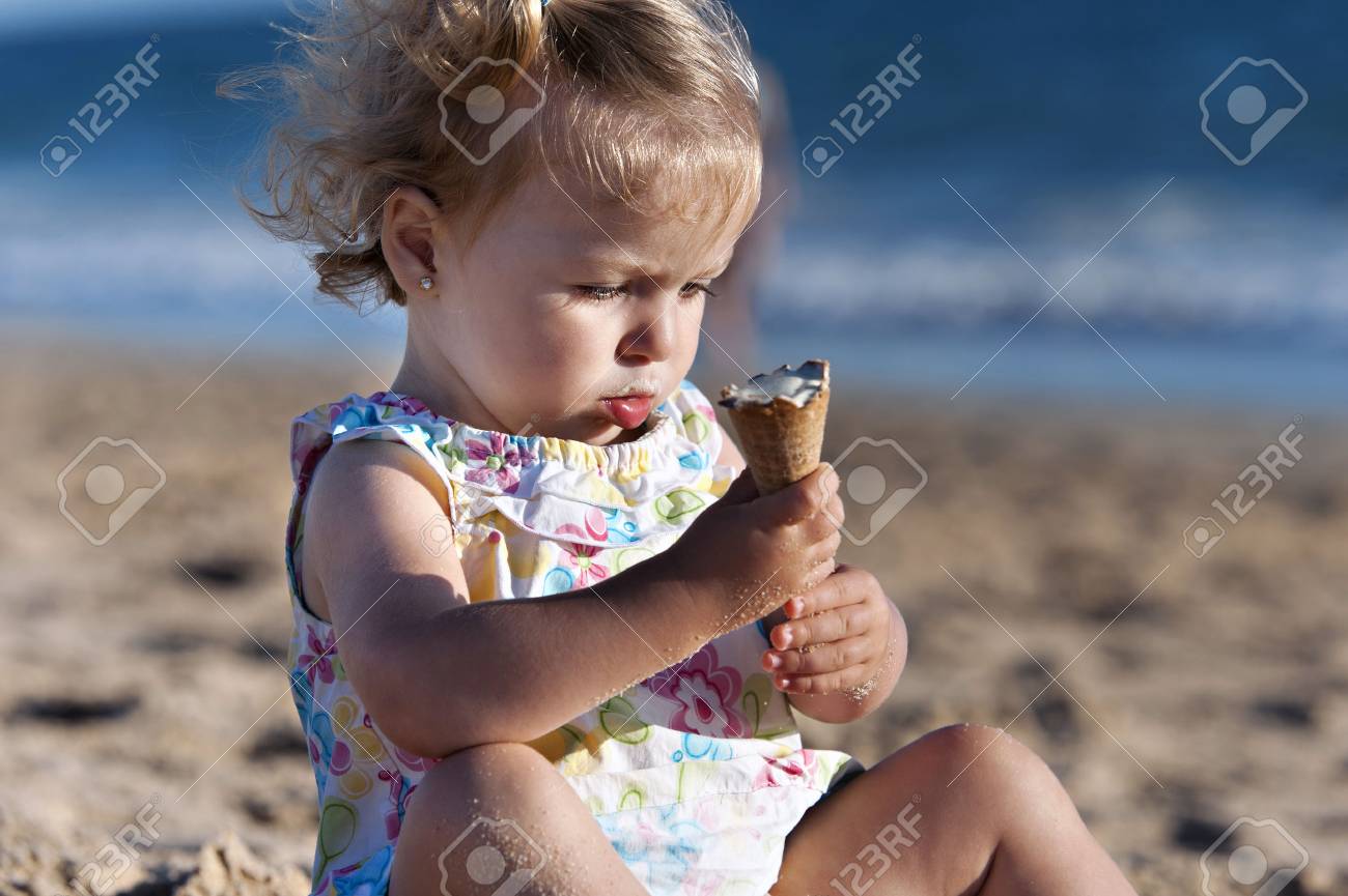 Small girl taking an ice cream in the beach - 38160257 Small girl taking an ice cream in the beach - 38160257