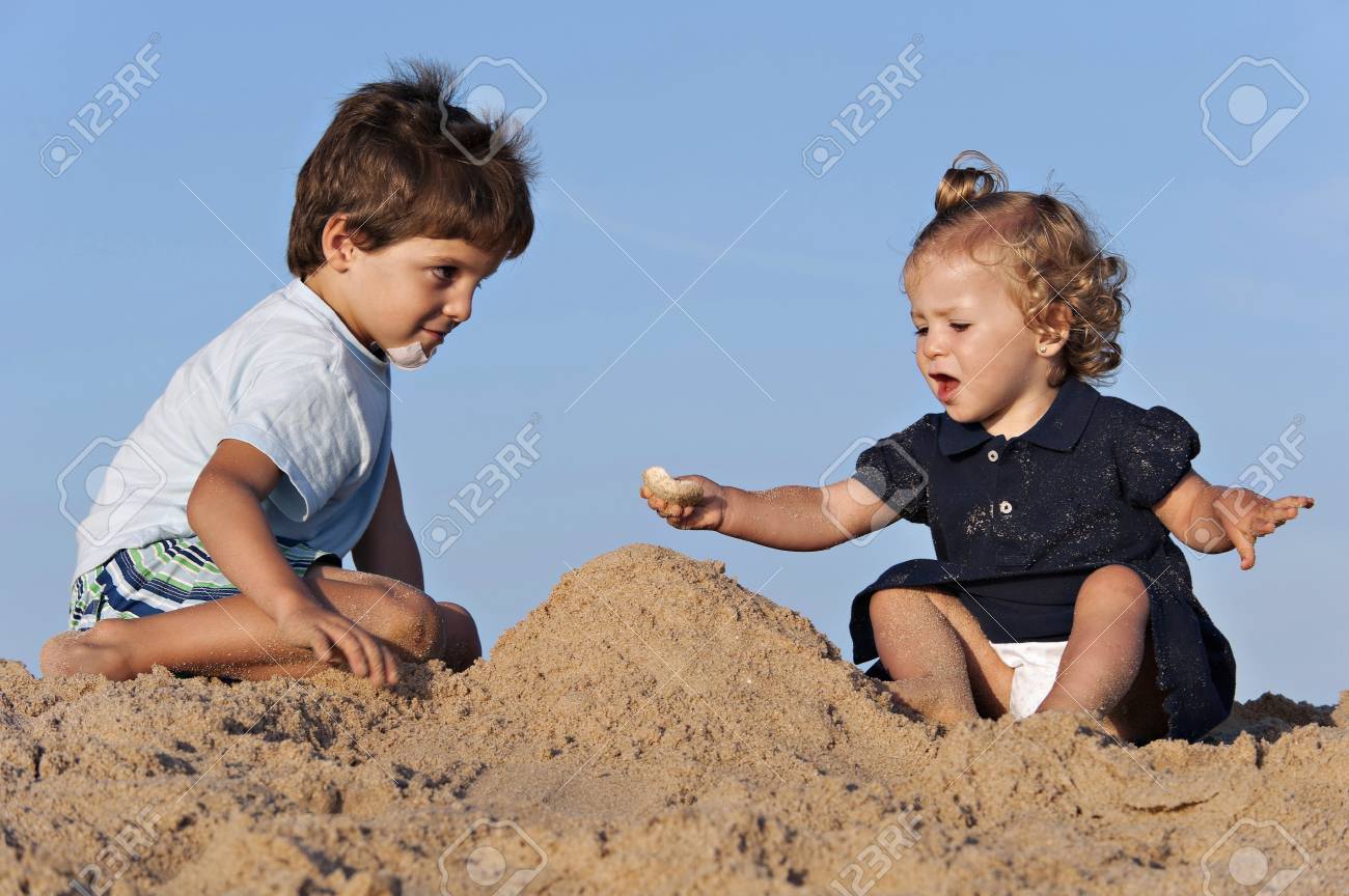 Two children have fun on the beach playing with the sand - 38161182 Two children have fun on the beach playing with the sand - 38161182