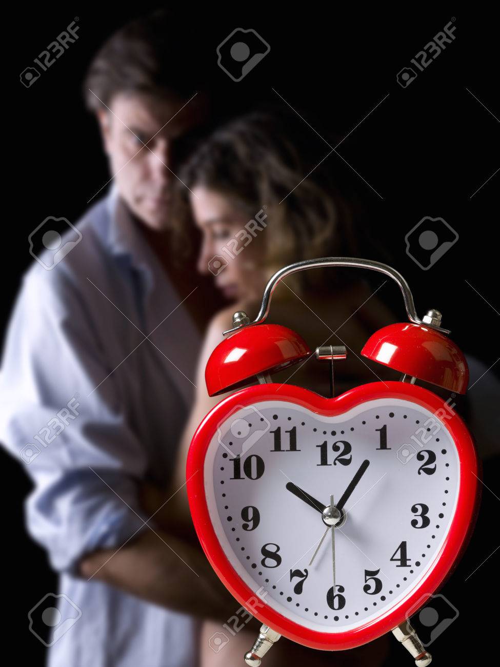 Clock and an embracing couple in the background - 38161380 Clock and an embracing couple in the background - 38161380