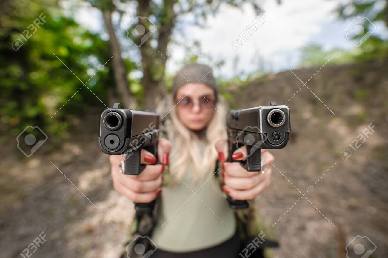 Attractive Soldier Woman Practice Shooting With Two Gun And Gun Point Aim  To Attacker. Abstract Close-up Pistol Wide Angle Pointing Front View. Nature  Outdoor Stock Photo, Picture And Royalty Free Image. Image