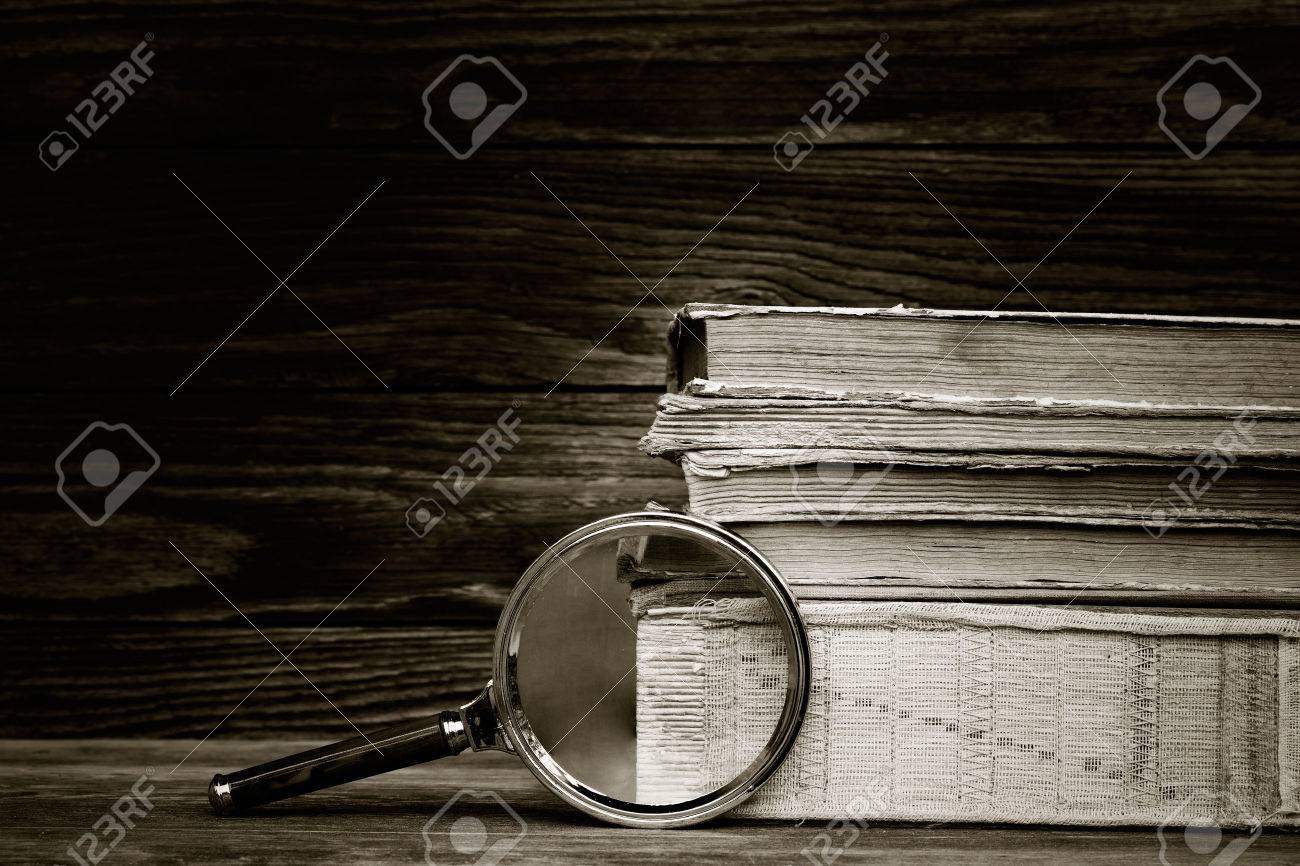 black and white photo. a pile of old books and magnifier on wooden background. the concept of the research, the study. with space for text - 56372426 black and white photo. a pile of old books and magnifier on wooden background. the concept of the research, the study. with space for text - 56372426