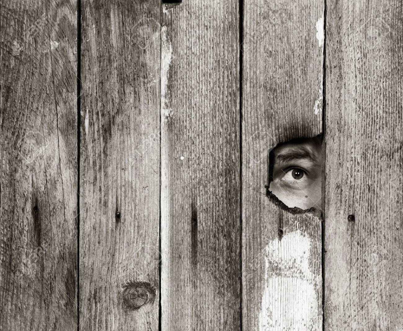 the eyes of a man spying through a hole in an old wooden fence. with space for posting information. black and white photo - 56429534 the eyes of a man spying through a hole in an old wooden fence. with space for posting information. black and white photo - 56429534