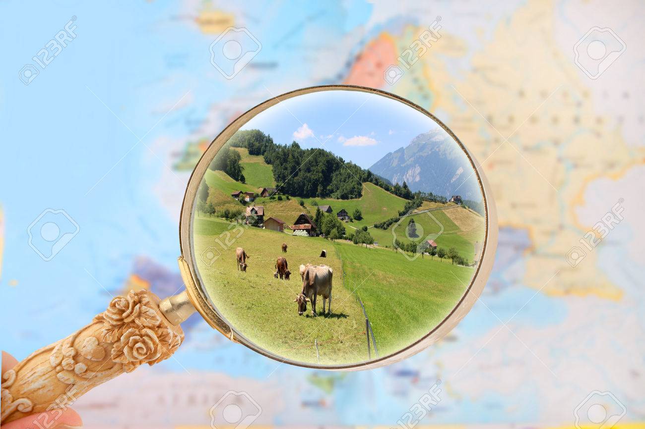 stock photo zooming on a map of europe with magnifying glass looking in on cattle in a farm switzerland europe