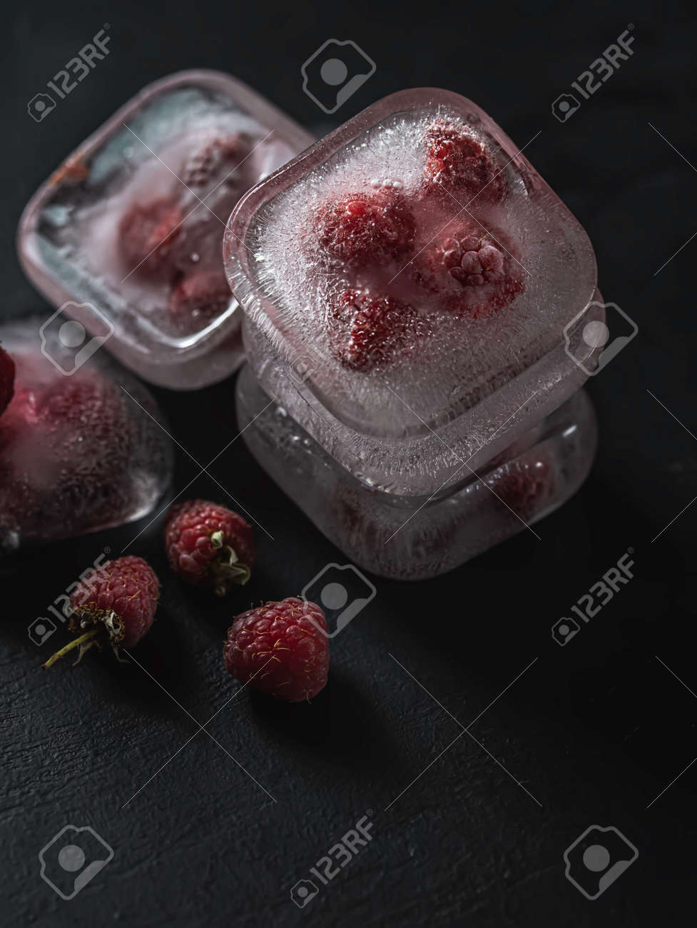 Raspberry frozen in the ice cube on black background. Fresh healthy summer eating. - 171671415 Raspberry frozen in the ice cube on black background. Fresh healthy summer eating. - 171671415