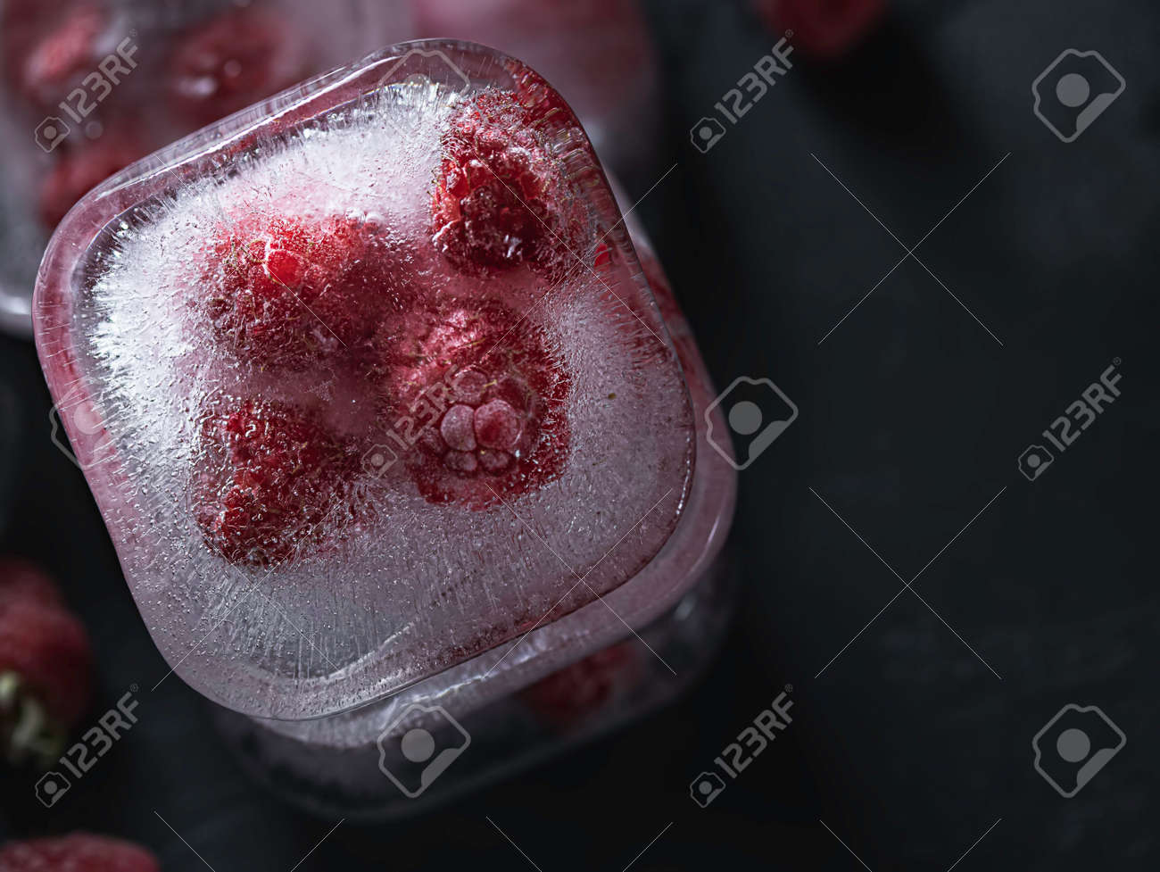 Raspberry frozen in the ice cube on black background. Fresh healthy summer eating. - 171671368 Raspberry frozen in the ice cube on black background. Fresh healthy summer eating. - 171671368