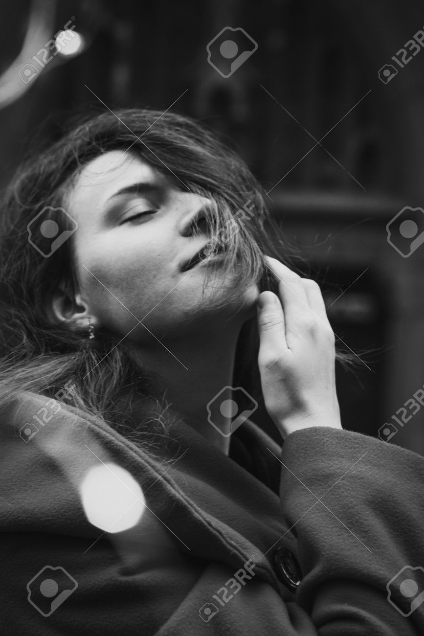 通りのモノクロのポートレート画像に美しい若い女性の接写。背景に古い