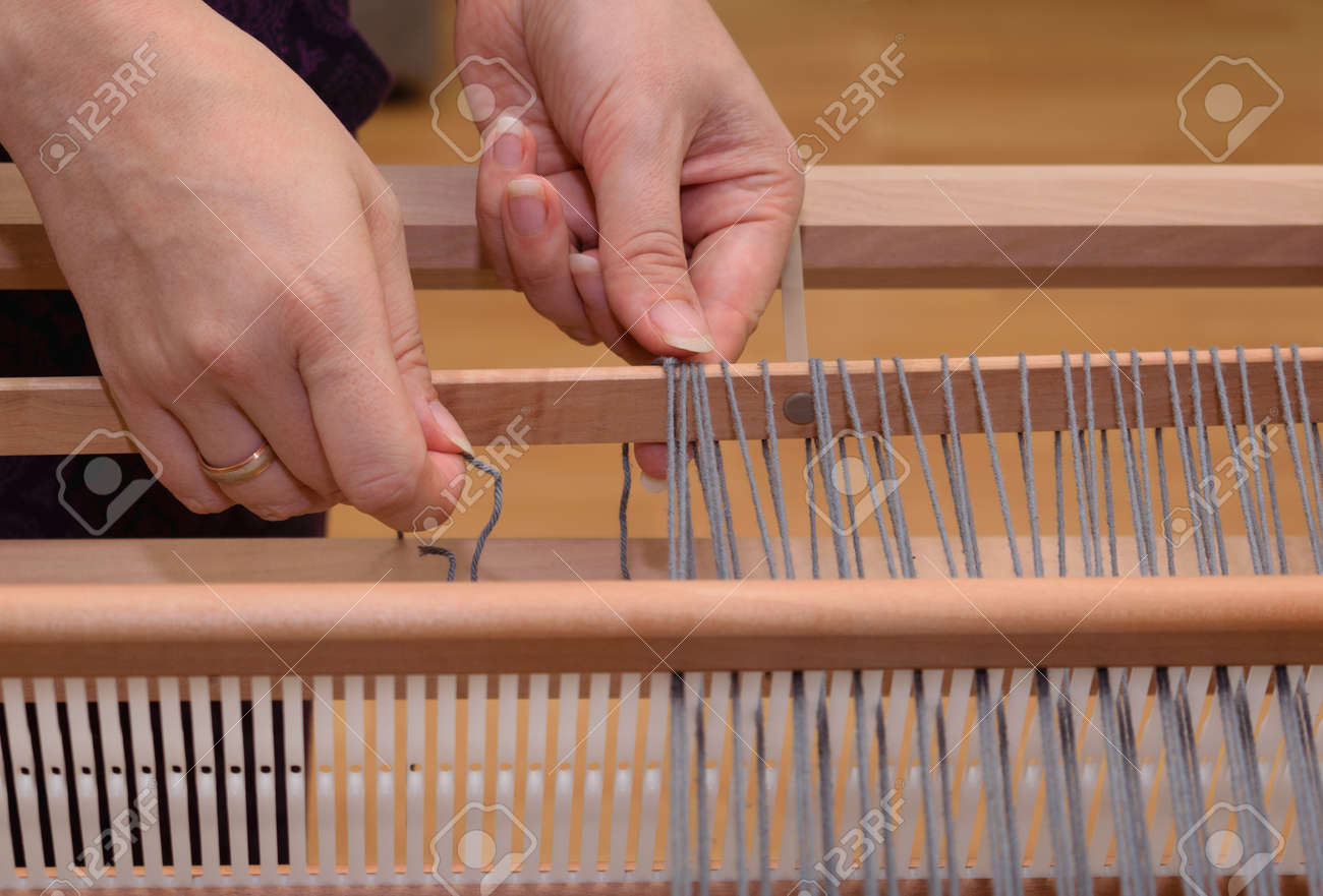Close up of a hand warping a rigid heddle loom - 108826619 Close up of a hand warping a rigid heddle loom - 108826619
