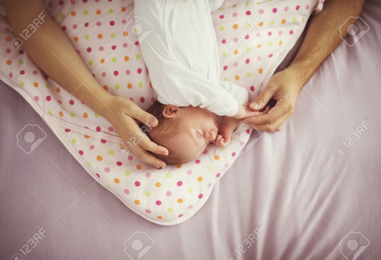newborn baby sleeping in bed with parents