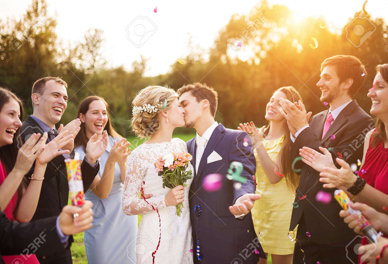 Full length portrait of newlywed couple and their friends at the wedding party showered with confetti in green sunny park - 35800941 Full length portrait of newlywed couple and their friends at the wedding party showered with confetti in green sunny park - 35800941