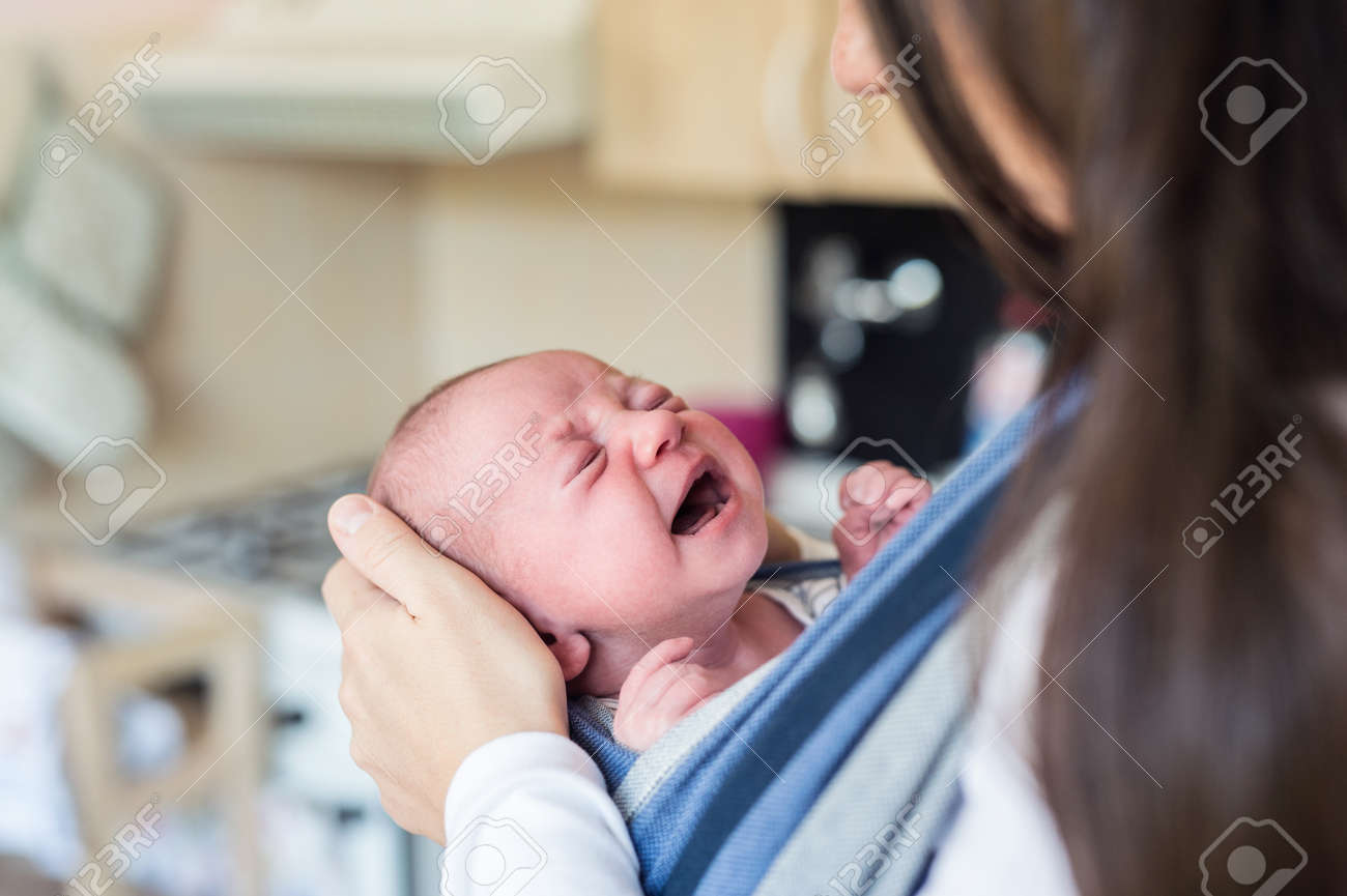 Close up of unrecognizable young mother with her crying newborn baby son in sling at home - 63827185 Close up of unrecognizable young mother with her crying newborn baby son in sling at home - 63827185