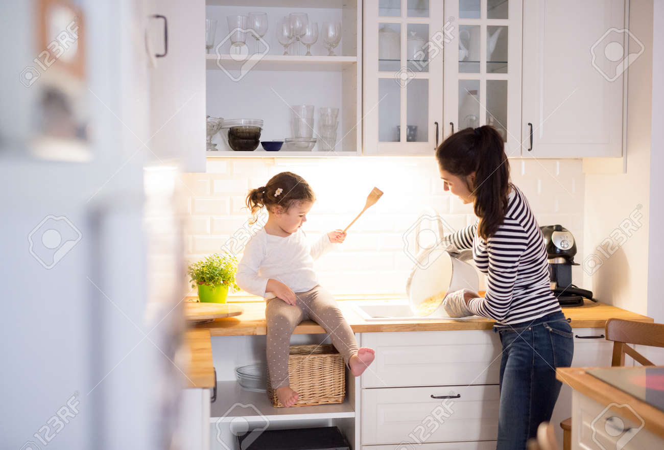 Beautiful young mother with her cute little daughter in the kitchen, cooking pasta together - 65973133 Beautiful young mother with her cute little daughter in the kitchen, cooking pasta together - 65973133