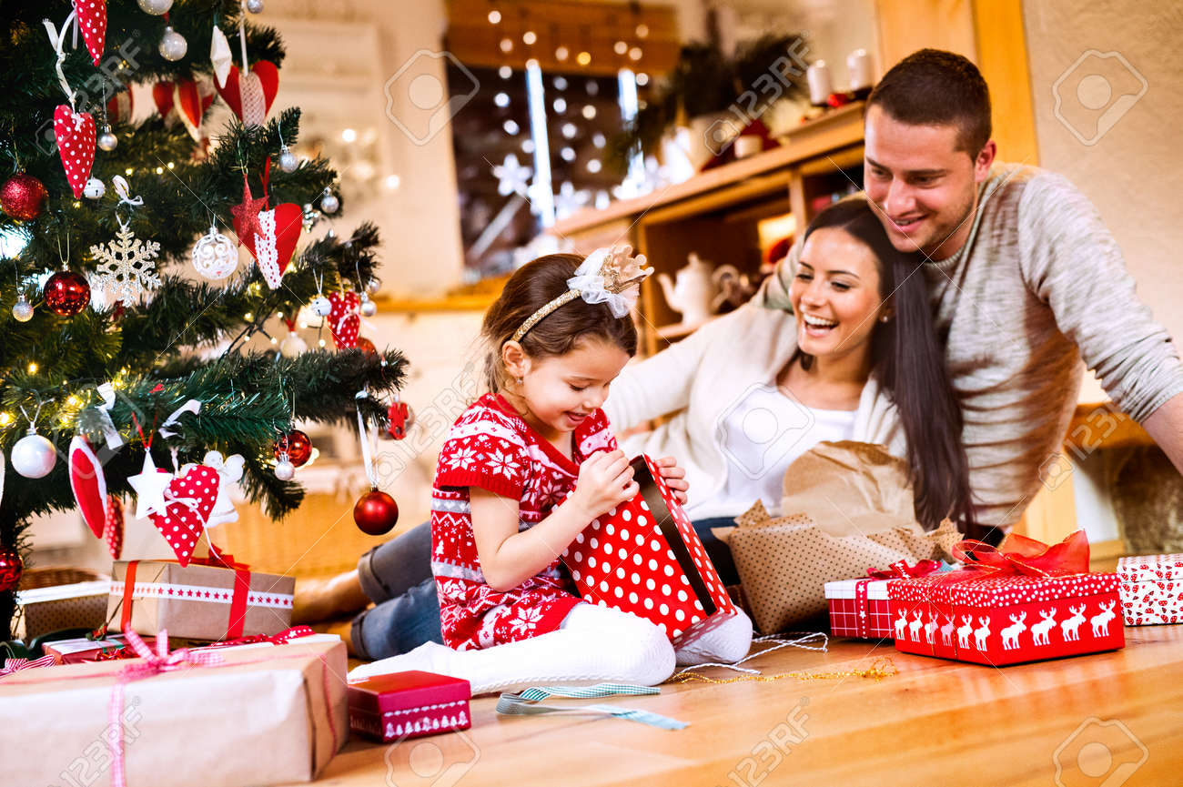 Young family with daughter at Christmas tree at home. - 87265310 Young family with daughter at Christmas tree at home. - 87265310