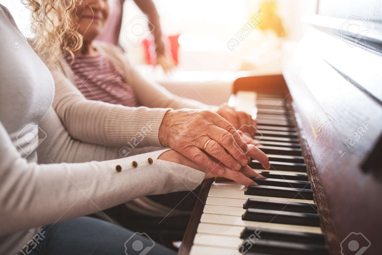 A girl with grandmother playing the piano. - 95243027 A girl with grandmother playing the piano. - 95243027